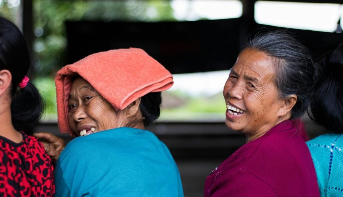 A portrait of two Indonesian women who are looking back toward the camera and smiling broadly