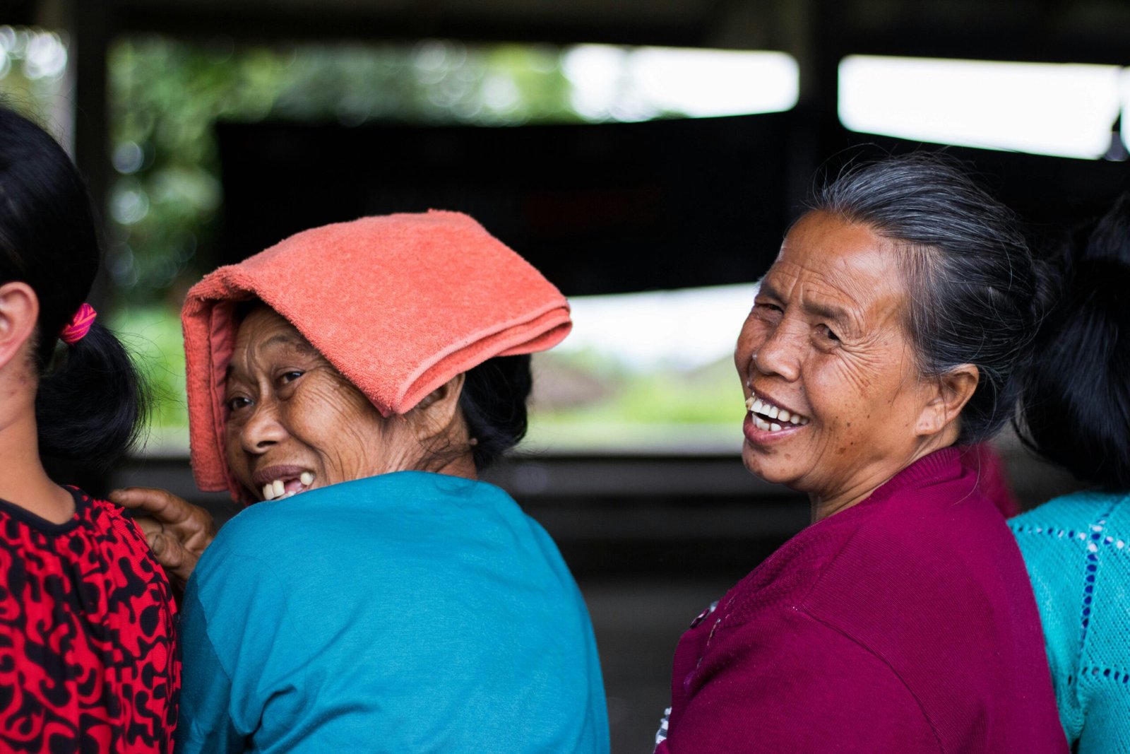 A portrait of two Indonesian women who are looking back toward the camera and smiling broadly